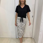 Woman wearing a black top and patterned skirt in an indoor setting