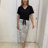 Woman wearing a black top and patterned skirt in an indoor setting