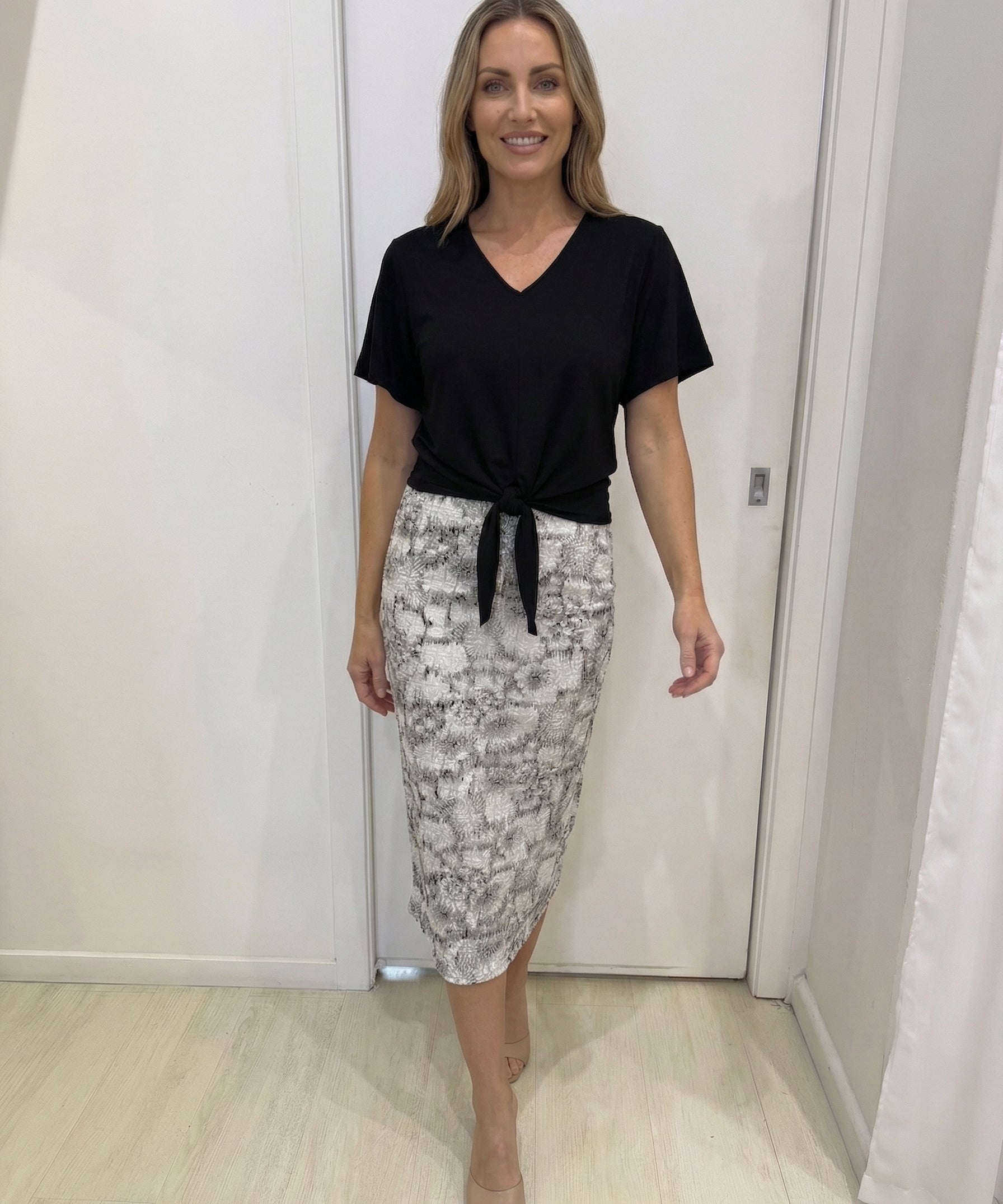 Woman wearing a black top and patterned skirt in an indoor setting