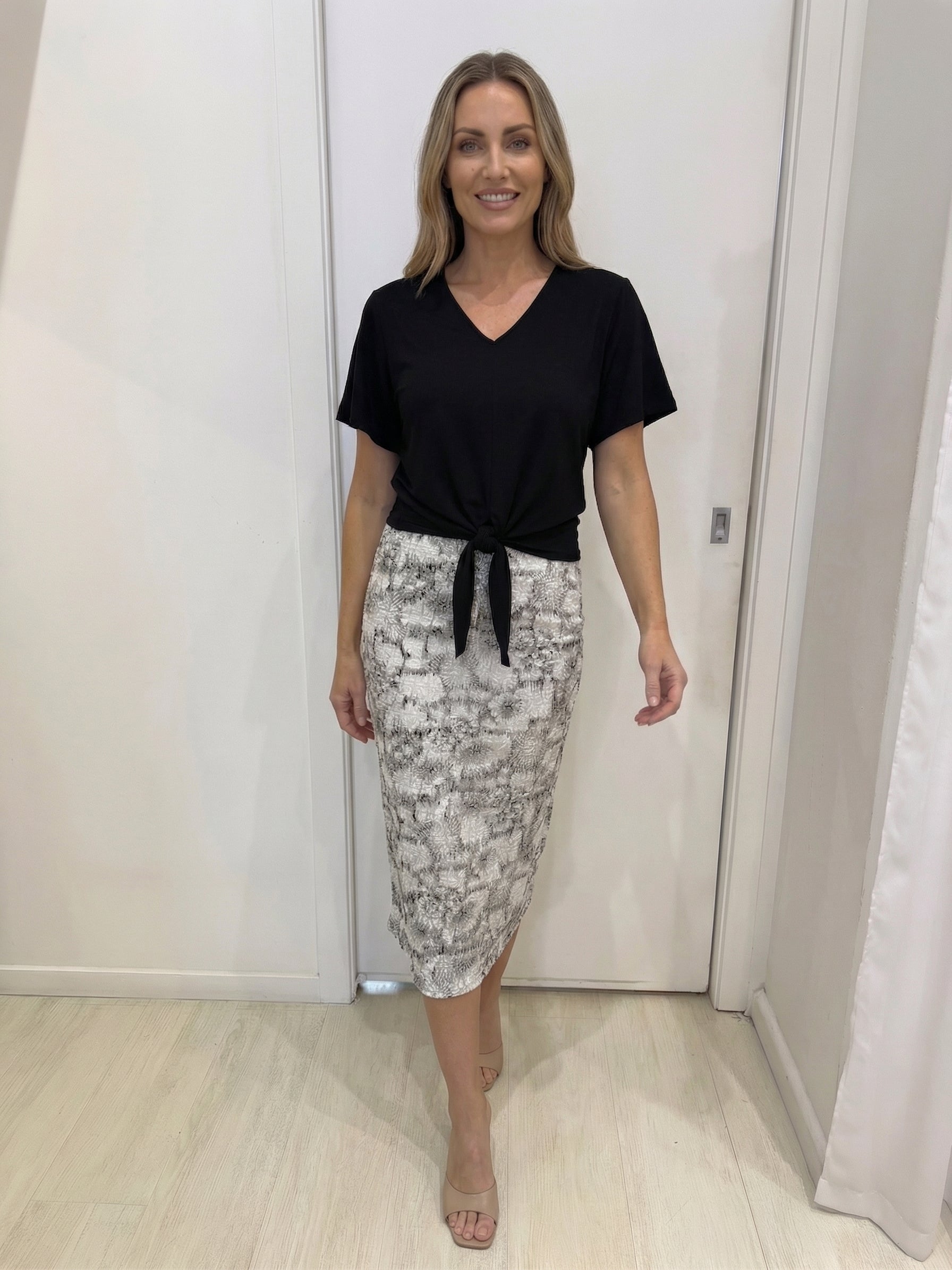 Woman wearing a black top and patterned skirt in an indoor setting