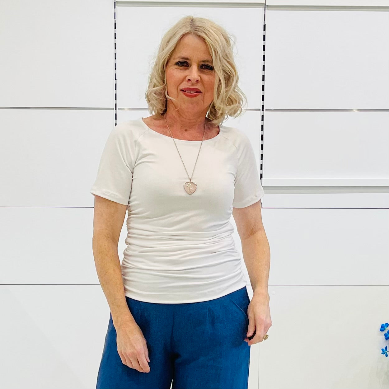 Woman wearing a white top and blue pants against a white background