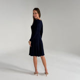 Woman wearing a navy blue dress on a plain background