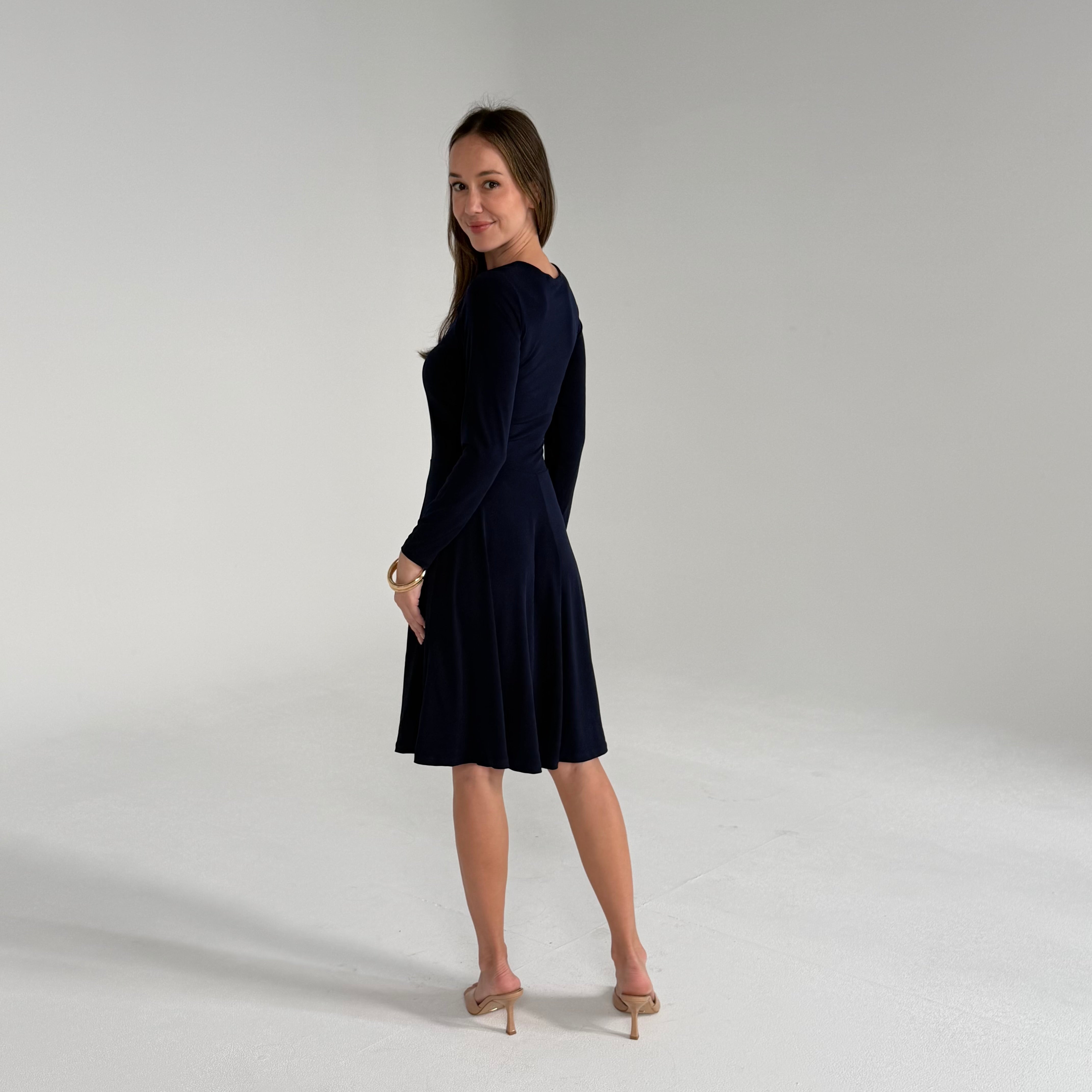 Woman wearing a navy blue dress on a plain background