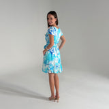 Woman wearing a blue floral dress on a plain background