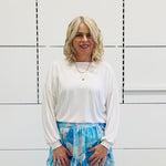 Relaxed, loose line fit, white bamboo, long sleeve with cuff and waistband shape, round neckline top. With blue skirt 