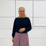 A woman wearing a black bamboo banded top with long sleeves and a knee-length red and black dotted skirt.