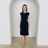 Woman wearing a black dress standing in a white archway.