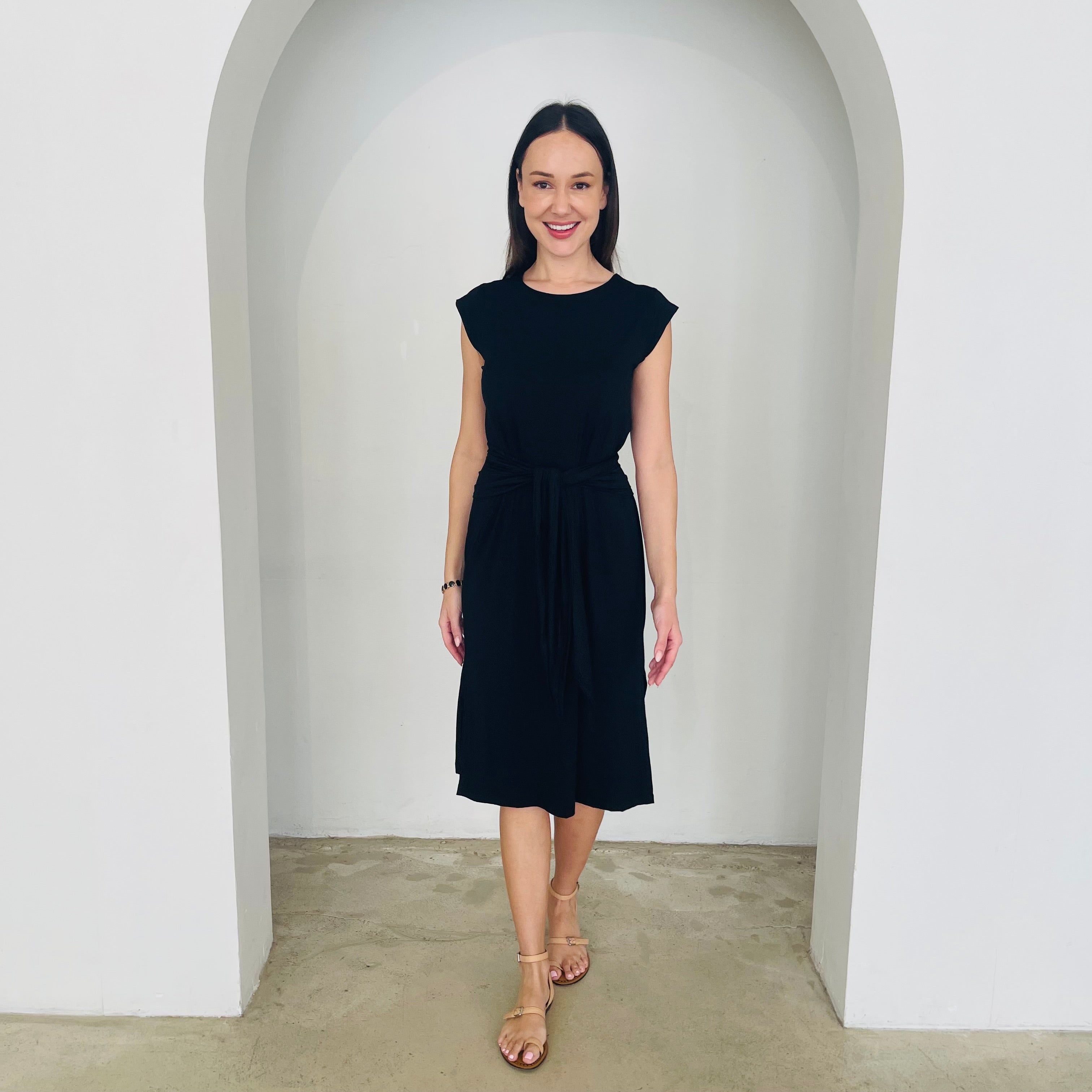 Woman wearing a black dress standing in a white archway.