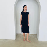 Woman wearing a black dress standing in a white archway.