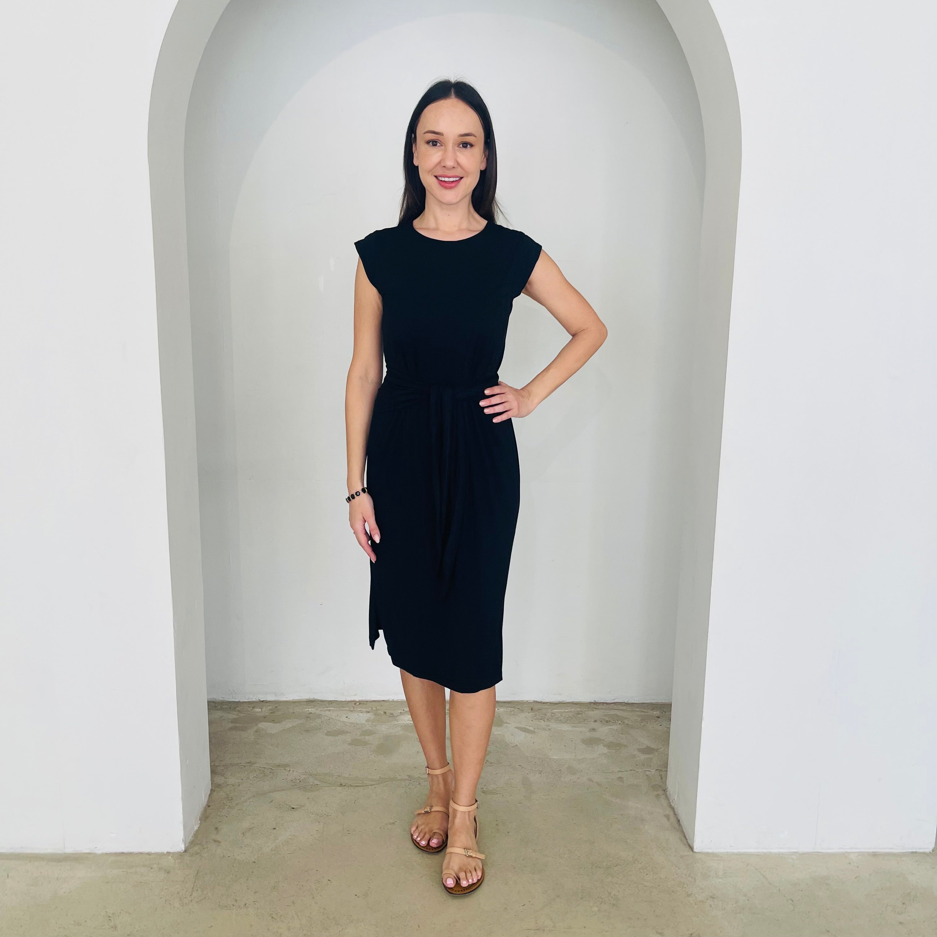 Woman wearing a black dress standing in a white archway.