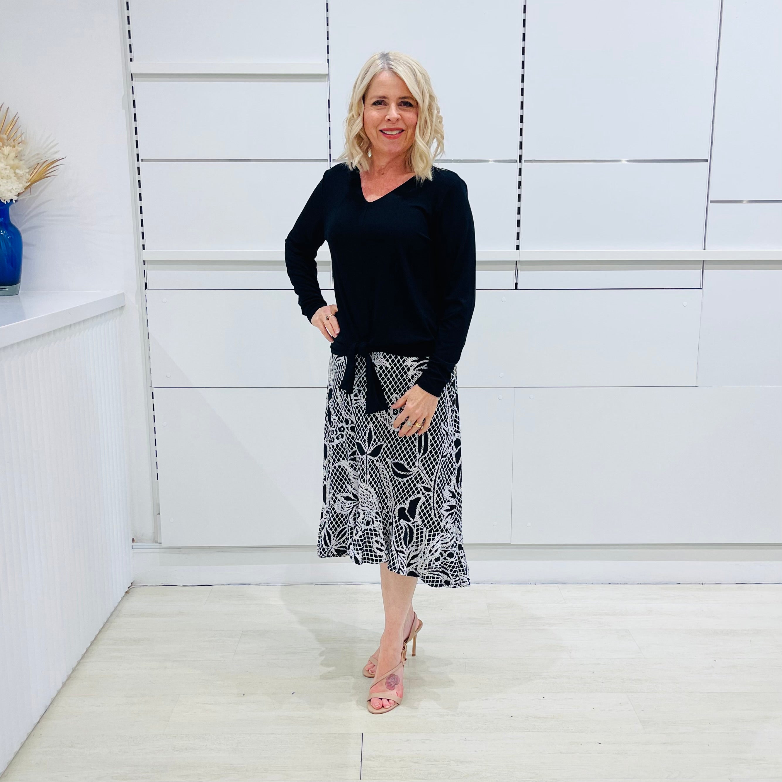 Noir garden-Black and white floral print, Rachel  Ruffle skirt, with elastic stretch waist. Worn on model with black bamboo , long sleeve, tie front, v-neckline top.