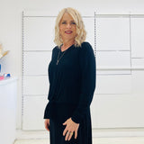 Relaxed fit, black bamboo, v neckline, long sleeve, tie front detail, dressy top. Worn with midi length skirt with slight hemline ruffle in black.