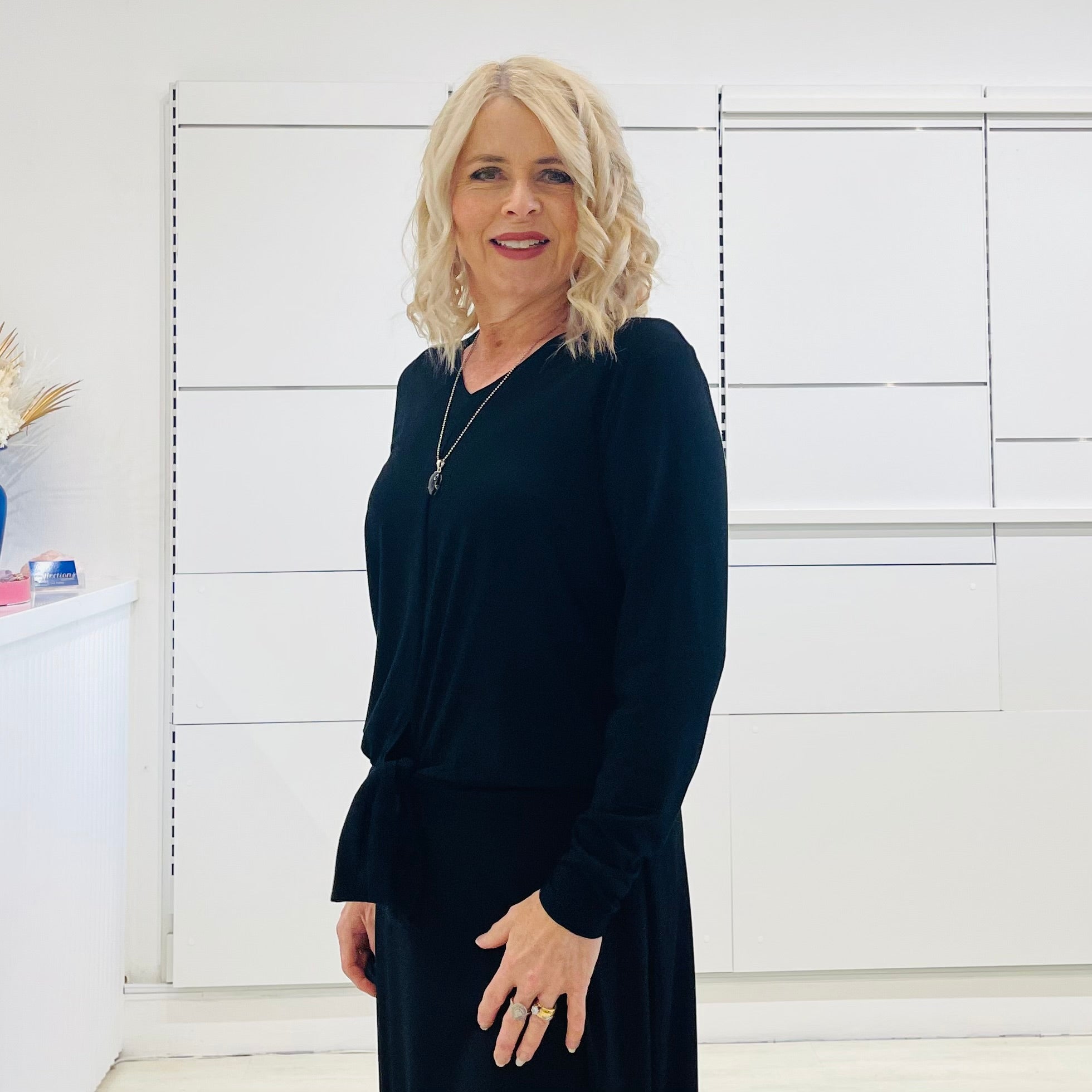 Relaxed fit, black bamboo, v neckline, long sleeve, tie front detail, dressy top. Worn with midi length skirt with slight hemline ruffle in black.