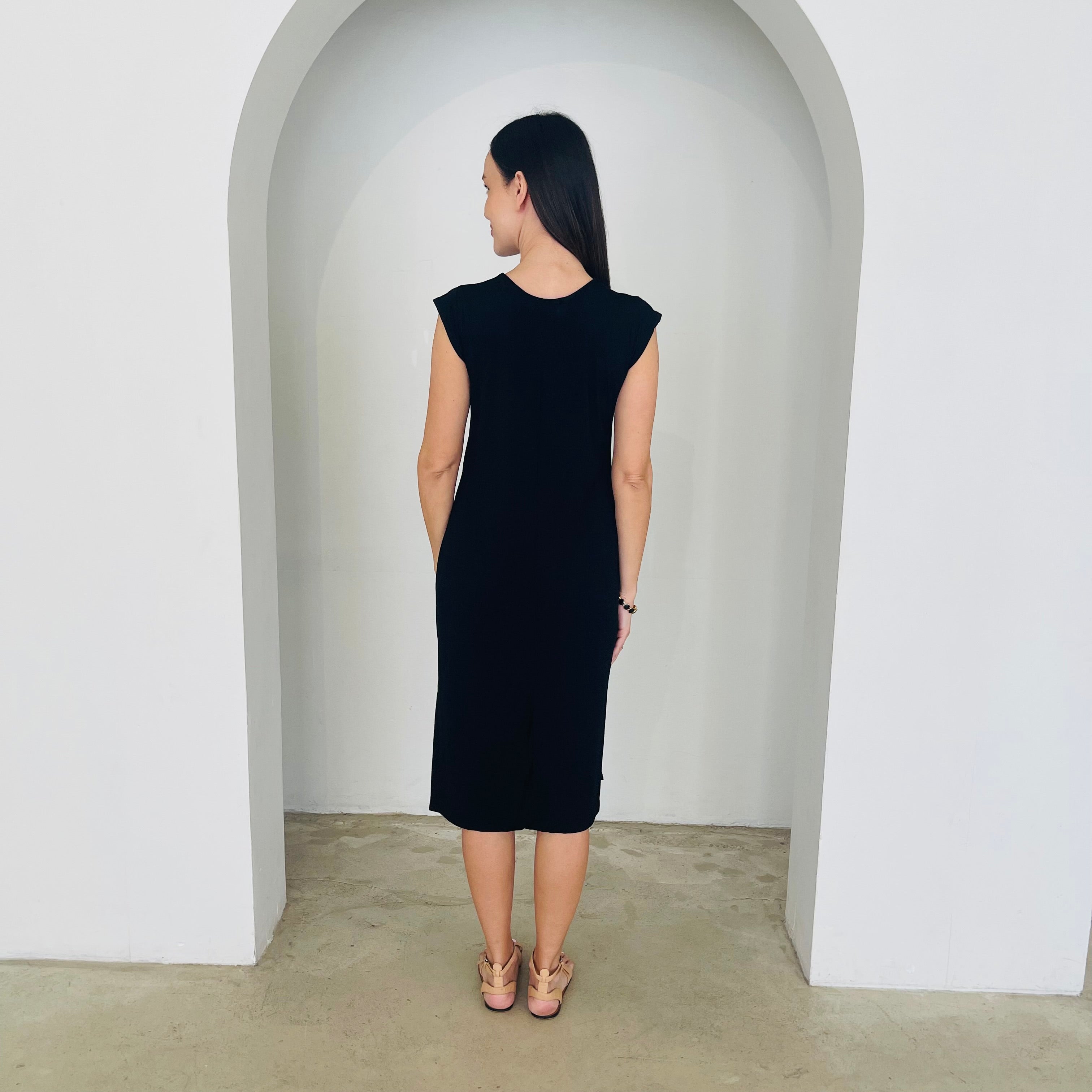 Woman wearing a black dress standing in a white archway.