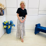 Woman standing in a room with a blue couch and flower arrangement.