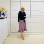Relaxed fit, black bamboo, v neckline, long sleeve, tie front detail, dressy top. Worn with midi length skirt with slight hemline ruffle in black,white and pink. 