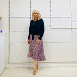 Relaxed fit, black bamboo, v neckline, long sleeve, tie front detail, dressy top. Worn with midi length skirt with slight hemline ruffle in black,white and pink. 