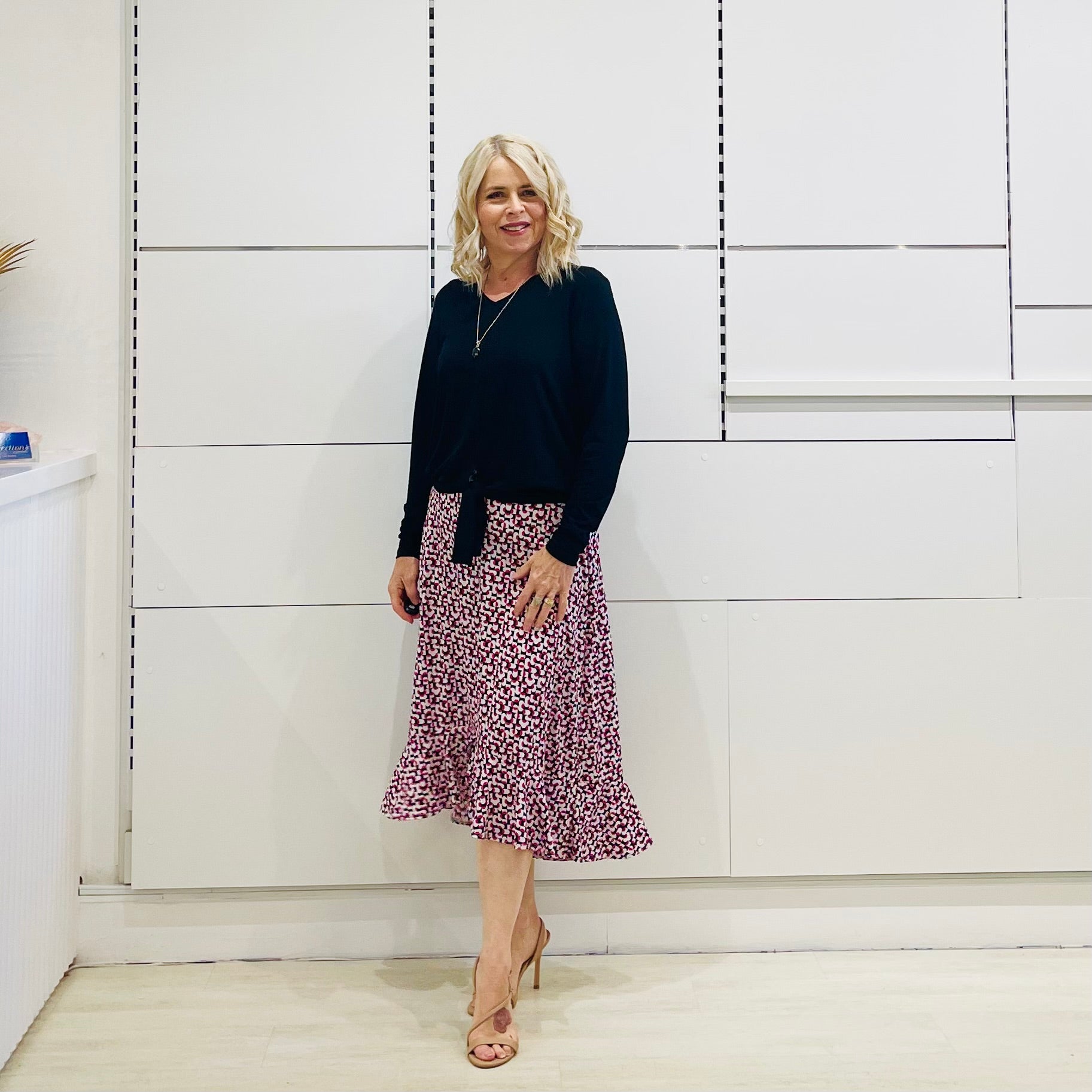 Relaxed fit, black bamboo, v neckline, long sleeve, tie front detail, dressy top. Worn with midi length skirt with slight hemline ruffle in black,white and pink. 