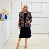 Black silk, with floral embroidery, collar, lapels, 3 button front closure, with pockets jacket. Worn with dressy straight black dress with side seam splits.