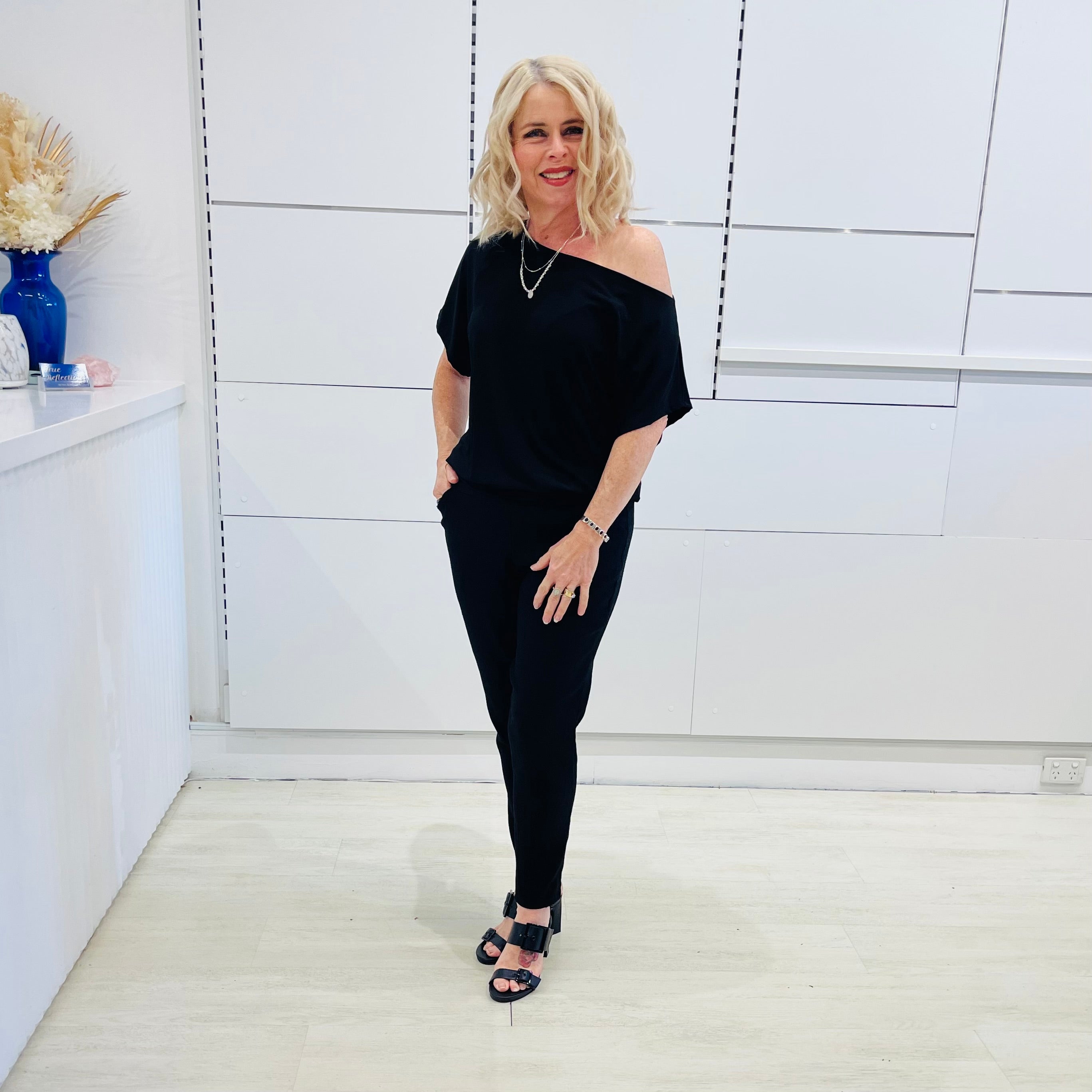 Black, textured fabric with subtle  Jaguar design pattern,  tapered leg pant with, pockets, stretch waistband, side seam invisible zipper opening. Black off the shoulder top.