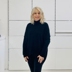 Relaxed fit loose line, long line, long sleeved, black knit jumper/sweater. With black pants and knee high leather boots 