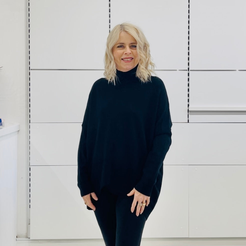 Relaxed fit loose line, long line, long sleeved, black knit jumper/sweater. With black pants and knee high leather boots 