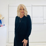 Relaxed fit, black bamboo, v neckline, long sleeve, tie front detail, dressy top. Worn with midi length skirt with slight hemline ruffle in black.