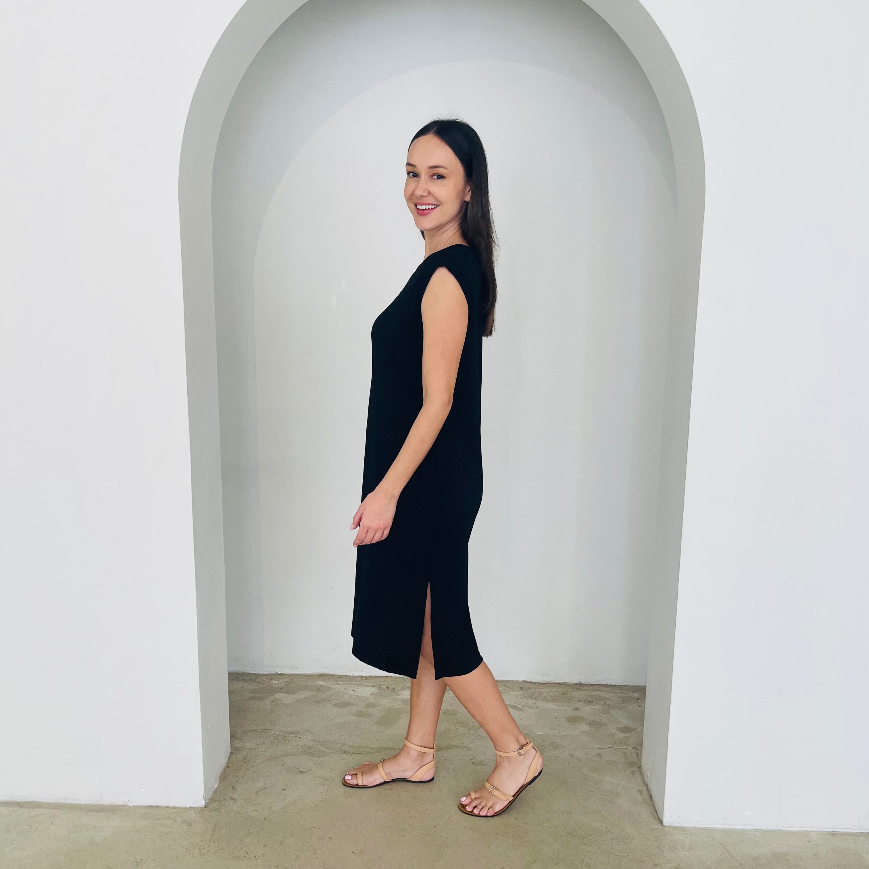 Woman in a black dress standing in a white archway