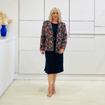 Black silk, with floral embroidery, collar, lapels, 3 button front closure, with pockets jacket. Worn with dressy straight black dress with side seam splits.