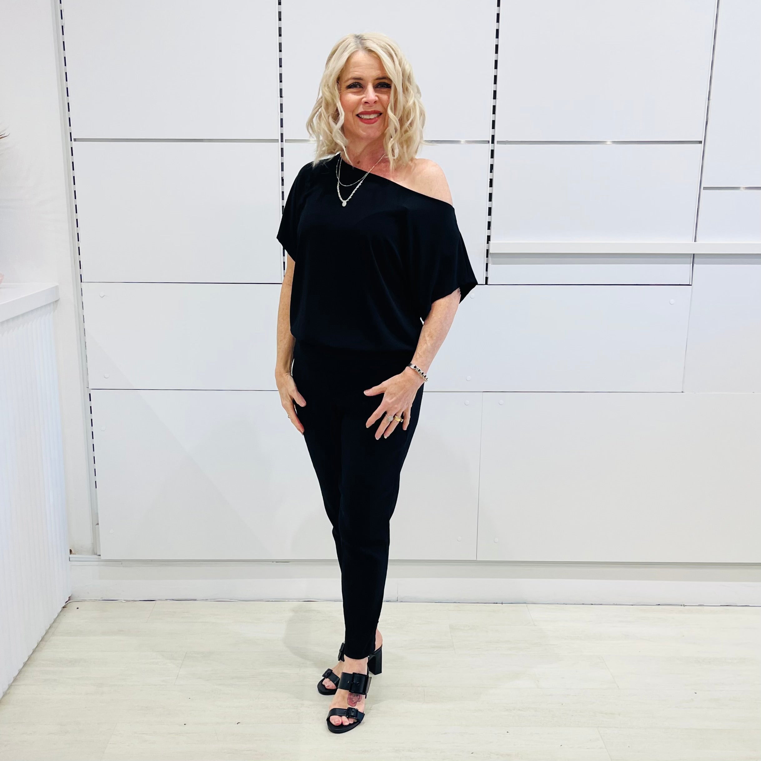 Black, textured fabric with subtle  Jaguar design pattern,  tapered leg pant with, pockets, stretch waistband, side seam invisible zipper opening. Black off the shoulder top.