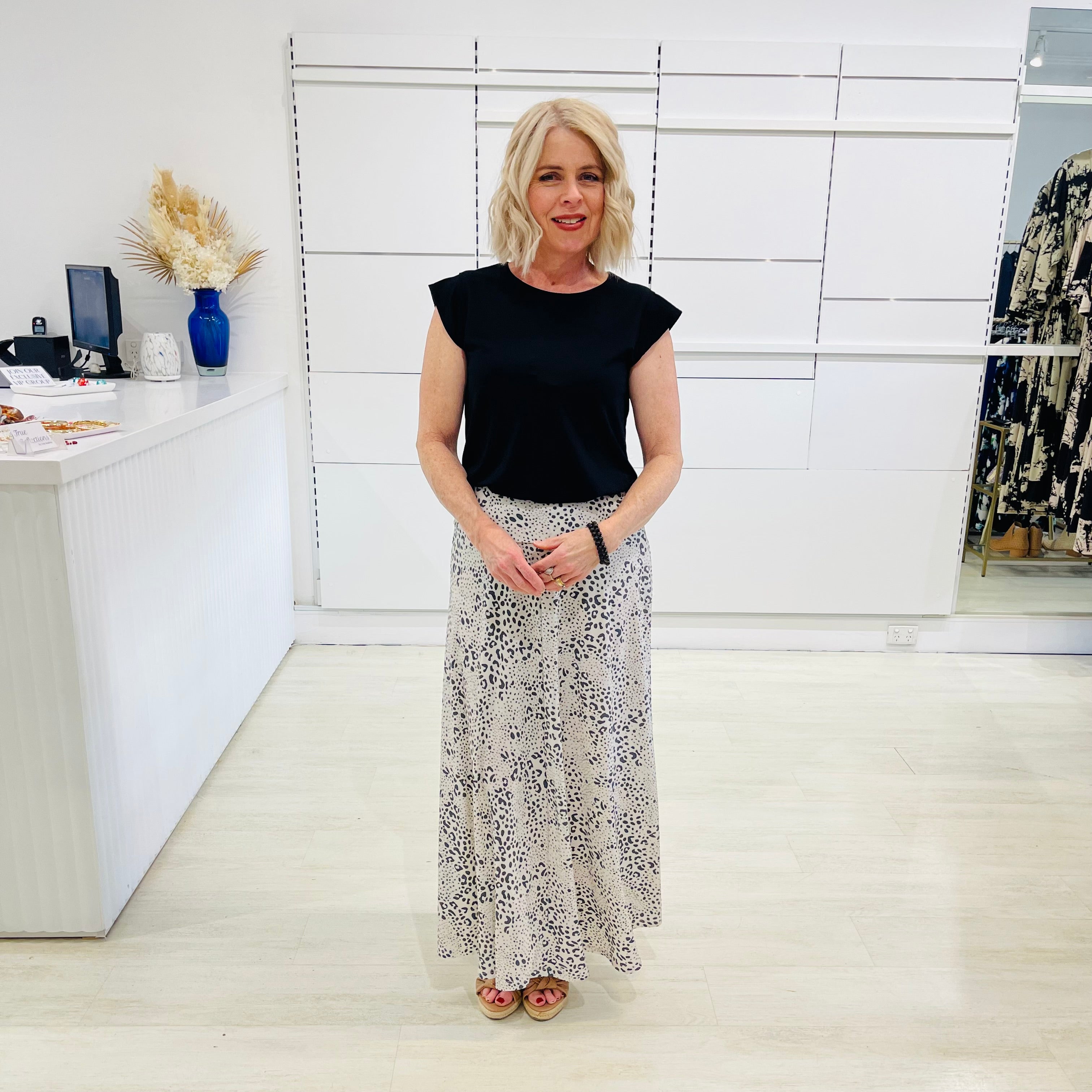 Woman in black top and patterned skirt standing in a modern office setting
