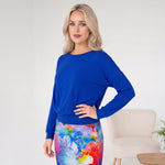 Woman wearing a blue top and colorful skirt in a minimalistic room.