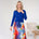 Woman wearing a blue top and colorful skirt in a minimalistic room.