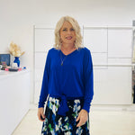 Relaxed fit, cobalt blue bamboo, v neckline, long sleeve, tie front detail, dressy top. Worn with midi length skirt with blue, black, white pattern print.