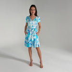 Woman wearing a blue and white patterned dress on a gray background