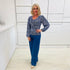 Woman wearing a flowy blue top with a delicate leaf print, paired with denim blue colored linen pants.