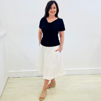 Black, bamboo, short sleeve, cowl neckline women's top, worn with white linen, midi length a line skirt with pockets and lace detail.