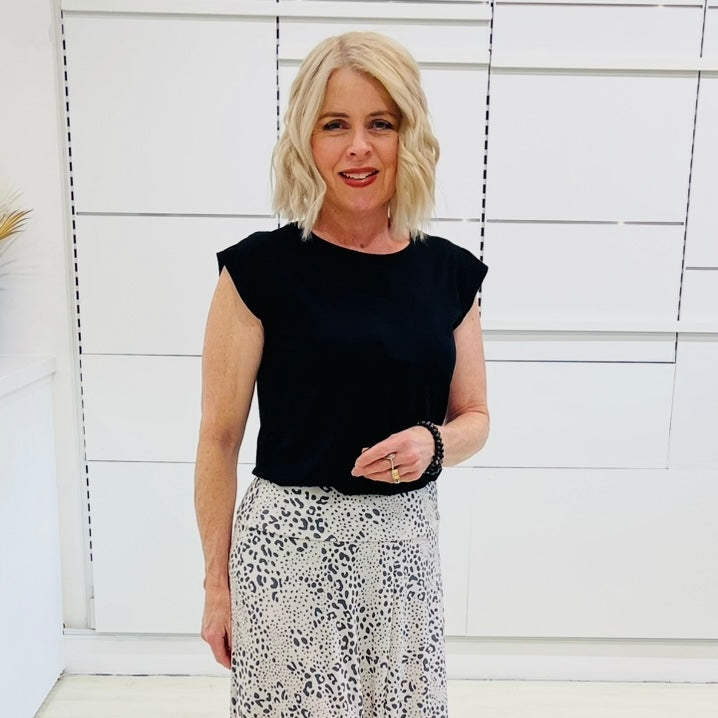 Woman wearing a black top and patterned skirt against a white background