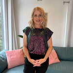 Woman wearing a sequin top sitting on a couch in a living room.