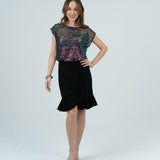 Model in white room with colourful top and black mini skirt 