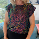 Person wearing a multicolored sequin top in an indoor setting