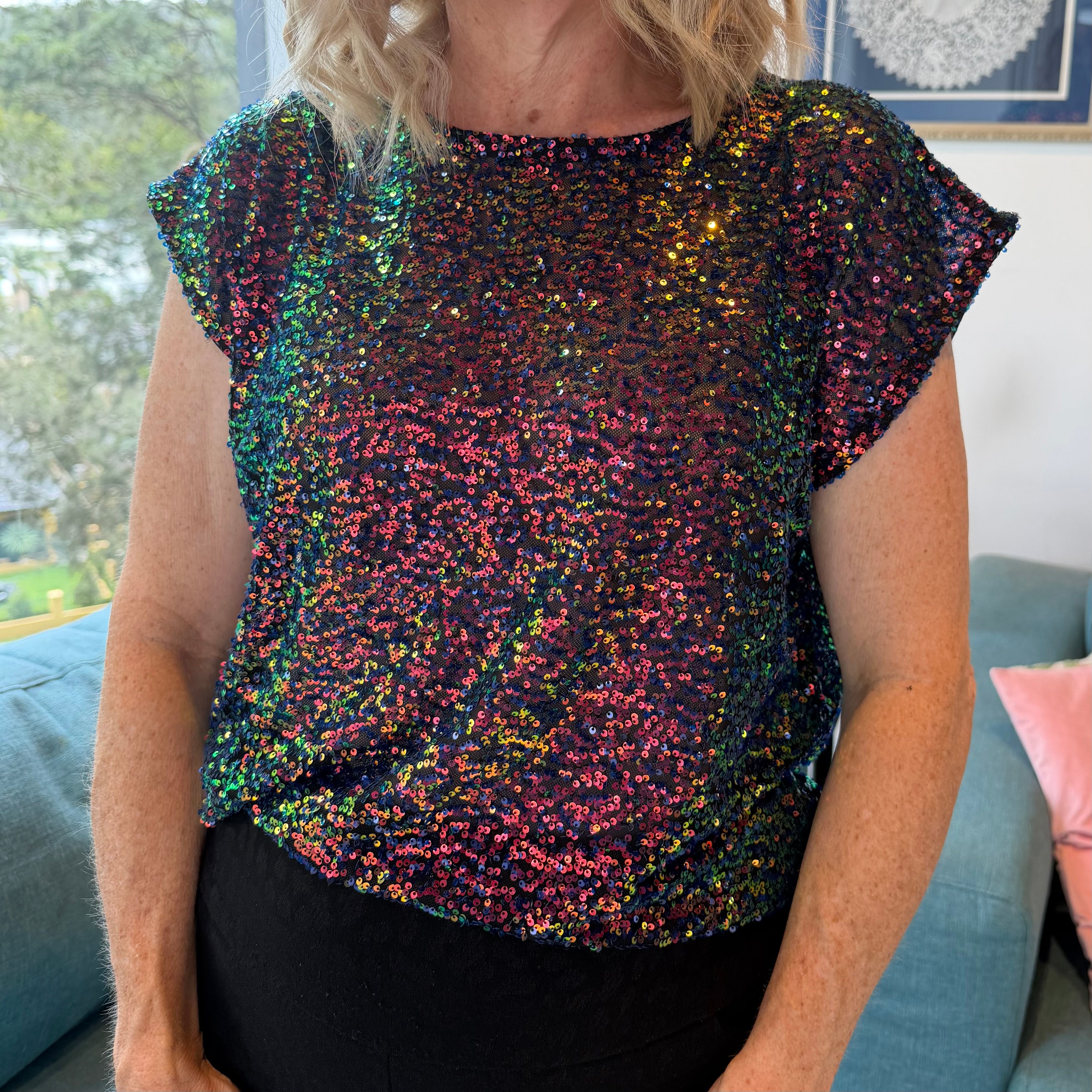 Person wearing a multicolored sequin top in an indoor setting