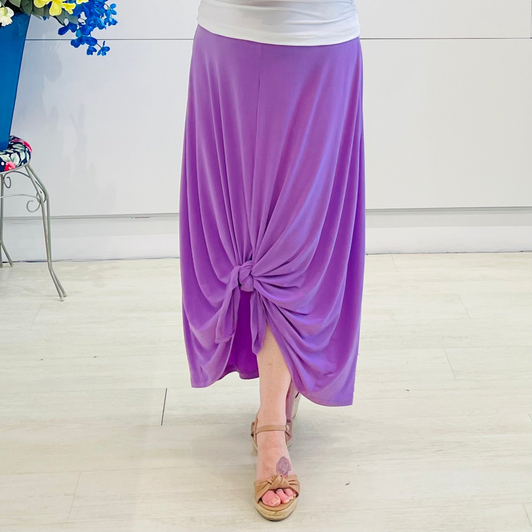 Person wearing a purple skirt with a knot detail on a light wooden floor.