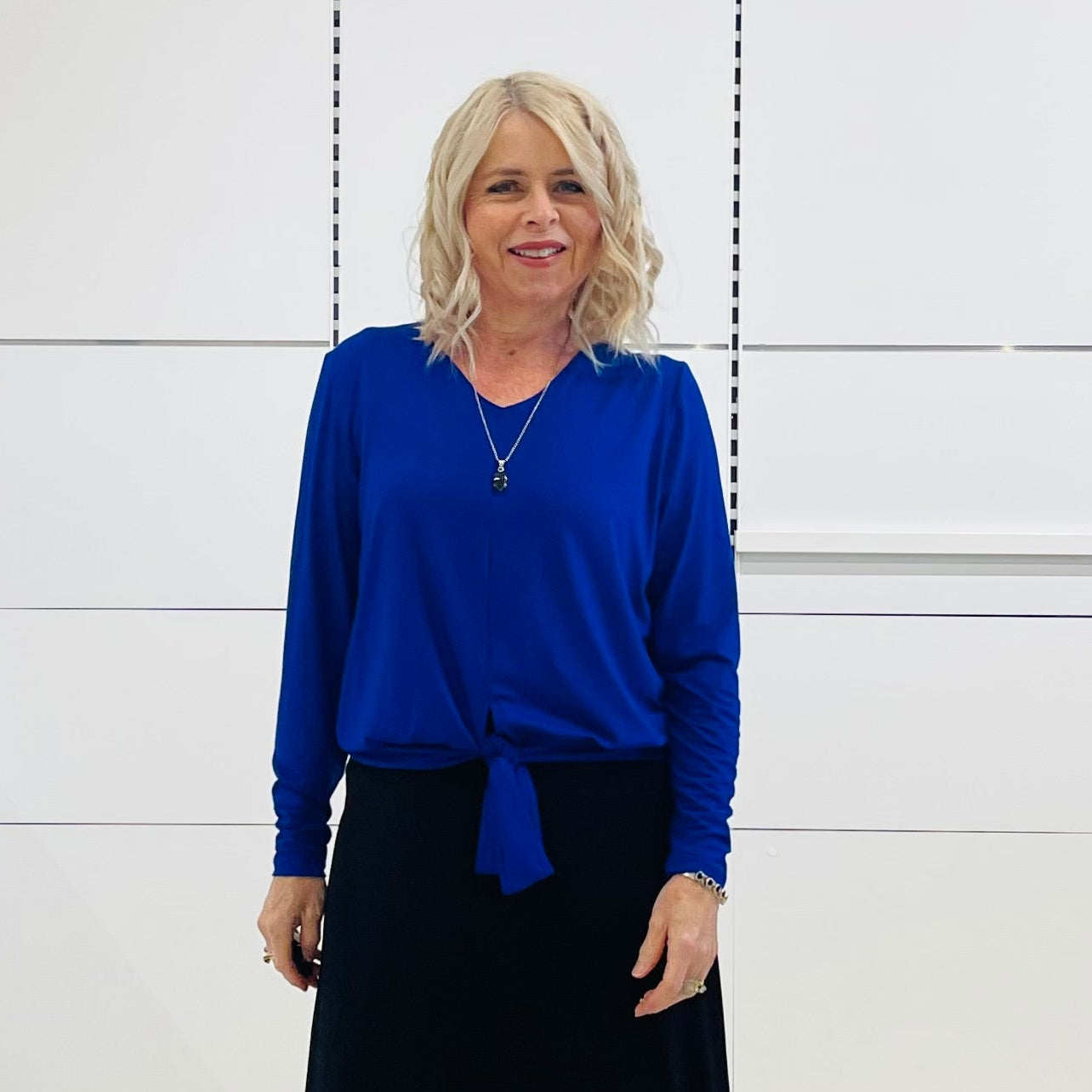 Relaxed fit, cobalt blue bamboo, v neckline, long sleeve, tie front detail, dressy top. Worn with midi length skirt with slight hemline ruffle in black.