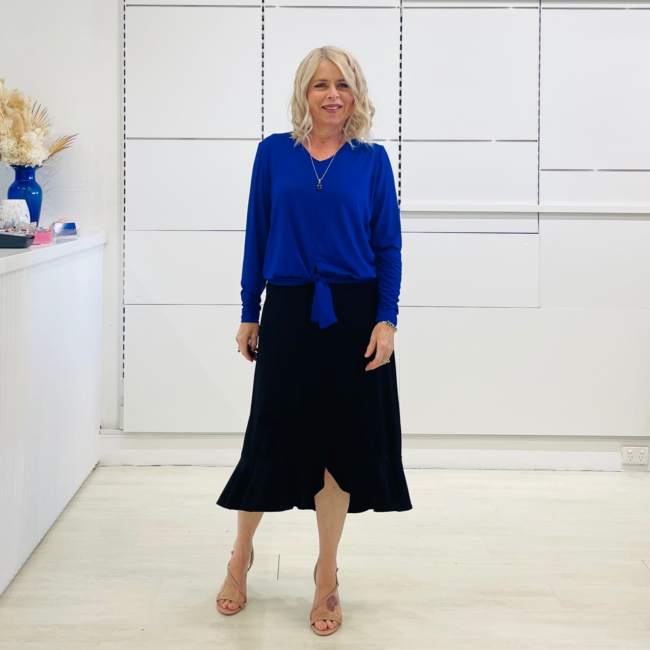 Relaxed fit, cobalt blue bamboo, v neckline, long sleeve, tie front detail, dressy top. Worn with midi length skirt with slight hemline ruffle in black.