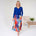 Woman wearing a blue top and colorful skirt in a minimalistic room.