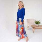 Woman wearing a blue top and colorful skirt in a minimalistic room.