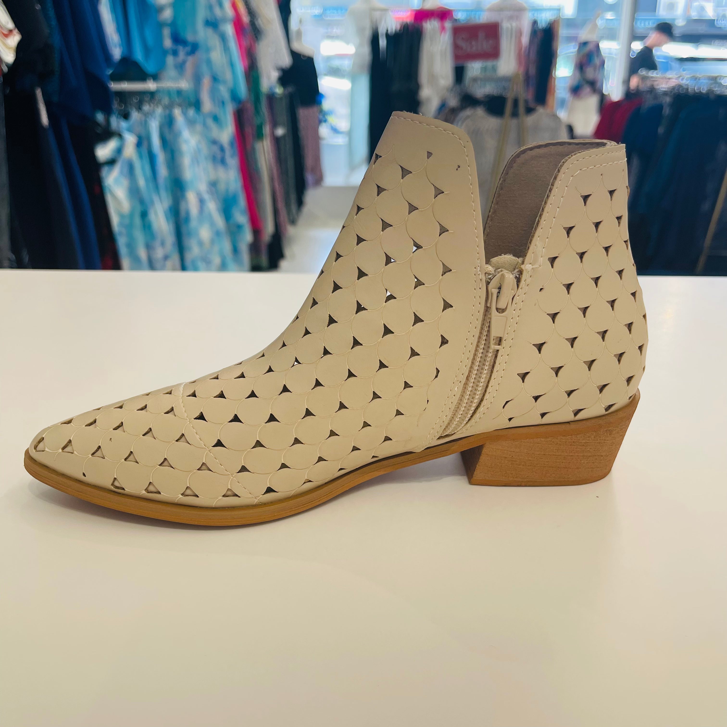 Intricate cut out design on cream colored man made leather ankle boots. Low 4cm heel. Zipper opening on side.