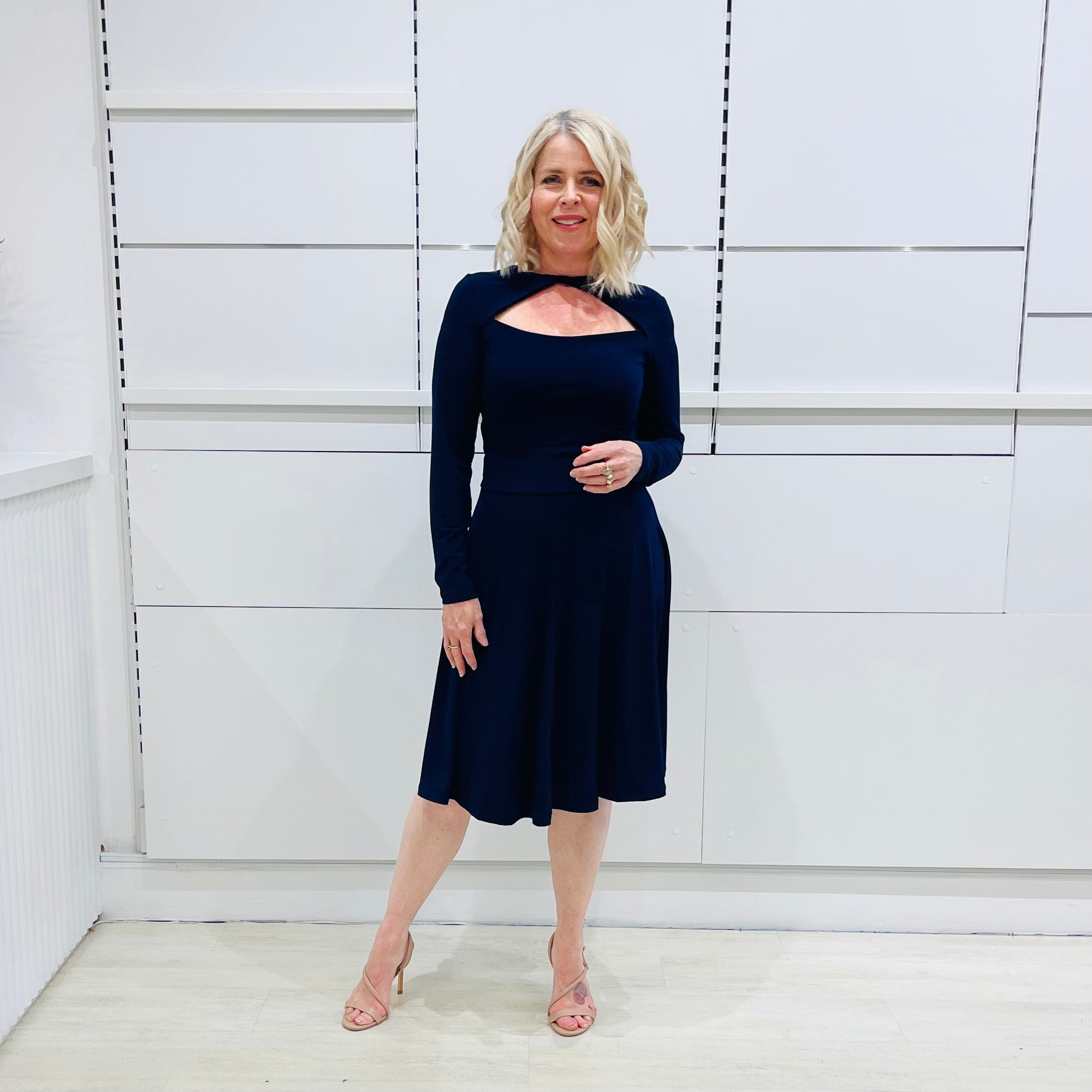 Penelope dress in deep navy blue, worn by model- elegant long sleeve design, knee length, with modern neckline.