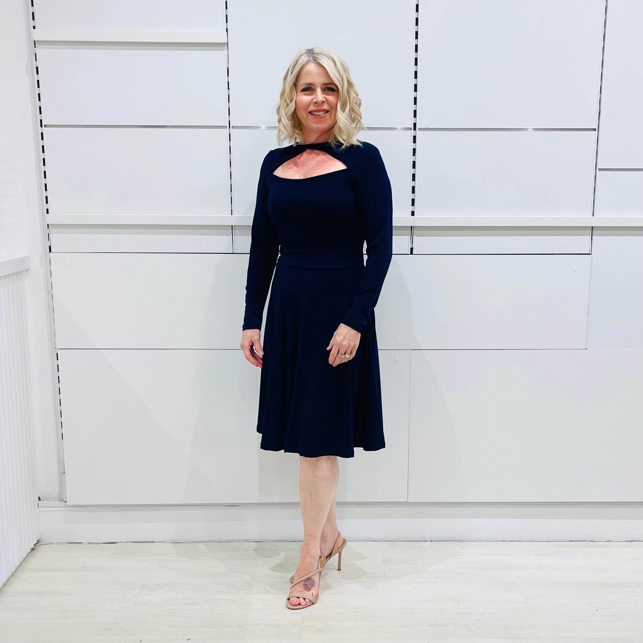Penelope dress in deep navy blue, worn by model- elegant long sleeve design, knee length, with modern neckline.